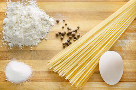 Spagetti on wood plate with eggs and saltの写真素材