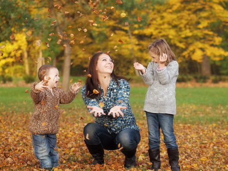 small children with mother playing in the park in autumn