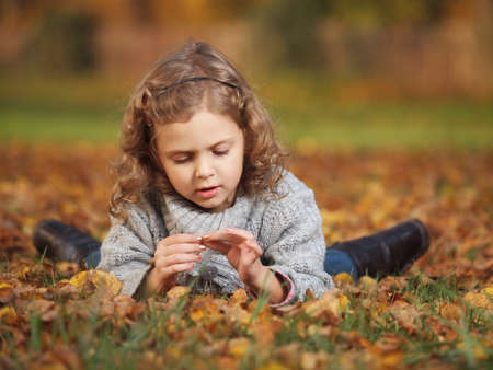 little girl playing in the park in autumnの写真素材