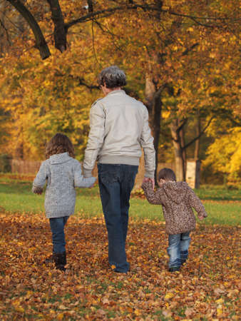 small children with grandfather playing in the park in autumnの写真素材