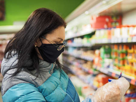 woman with protective mask on her face buys in a shopping center during a coronavir pandemicの写真素材