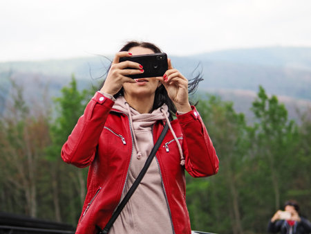young woman takes a selfie on a background of mountains