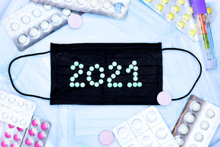 Numbers 2021 from blue pills against a black mask background, flatlay