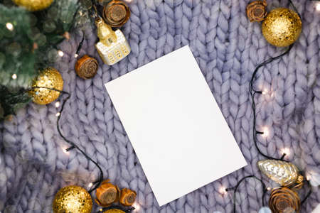 White sheet of paper on a gray knitted background among New Year's decorations, flat layの写真素材