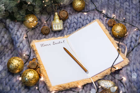 Notepad with the inscription dear santa on a gray knitted background with christmas balls, flat layの写真素材