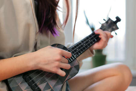 Womens teenagers hands play ukulele guitar, close-upの写真素材
