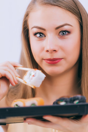 Beautiful girl trying Japanese food rolls, close-upの写真素材