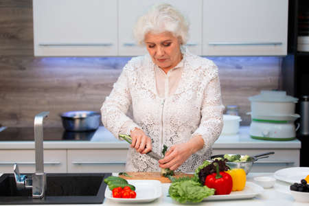 Caucasian woman pensioner cuts broccoli before cookingの写真素材