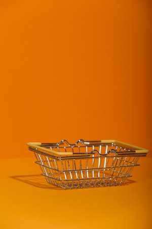Small metal empty grocery basket on orange background