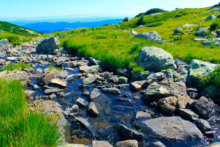 High mountain river running amongst big rocks in a sunny spring dayの写真素材