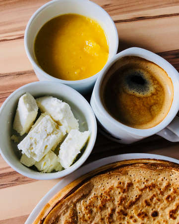 food Pancakes with local bee honey white cheese on focus and black coffee shot from aboveの写真素材