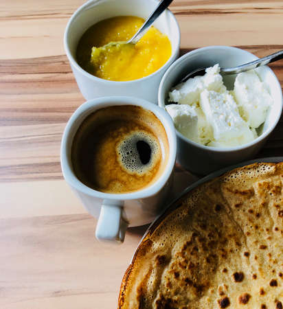 food Pancakes with local bee honey white cheese and black coffee on focus and spoons shot from aboveの写真素材