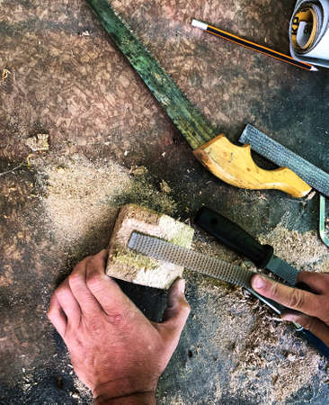 man working on a piece of wood rasping outdoors labor craft concept top view