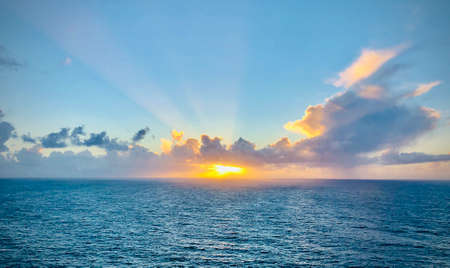 Romantic sunset over the ocean. Sunbeams passing through the clouds. Vivid colors horisontal shot