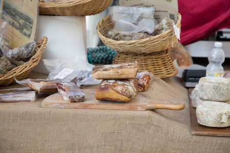 Assorted cheese and portions of cured meat on display on a stall in a street market or artisanal shopの写真素材