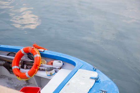 Bright orange life buoy, preserver or ring on a colorful blue and white boat with copy space over...