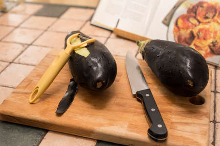 closeup of aubergines on wooden board with knife and stewerの写真素材