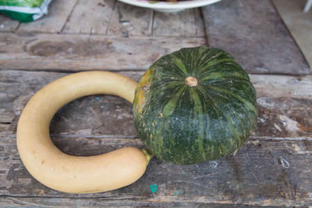 horizontal image with detail of two pumpkins photographed on an old wooden tableの写真素材