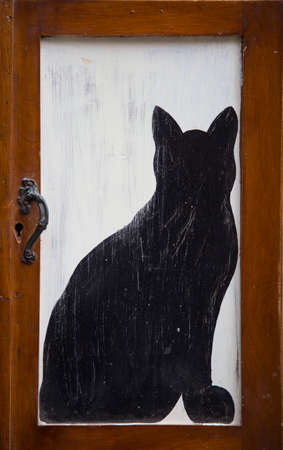 vertical image of a small door with drawn a black catの写真素材