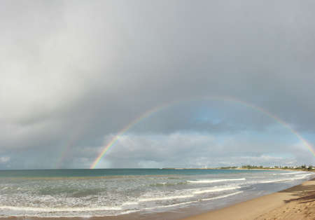 large complete full half circle rainbow stretching across the sky into the ocean at Apollo Bay, Victoria, Australiaの写真素材