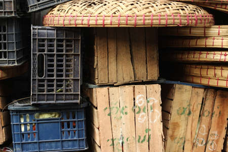 piles of timber and plastic food transport crates piled high by the side of the road at a market in...
