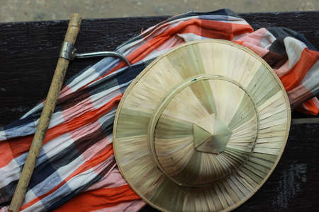 flat lay details showing the tools and colorful clothing and bamboo woven hat of a traditional Northern Thailand Thai Elephant Mahoot trainer, Southeast Asiaの写真素材