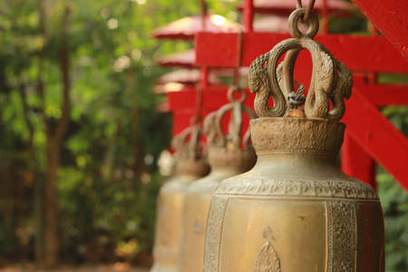 row of copper bells hanging at an ancient Buddhist temple, used traditionally to signal when a...
