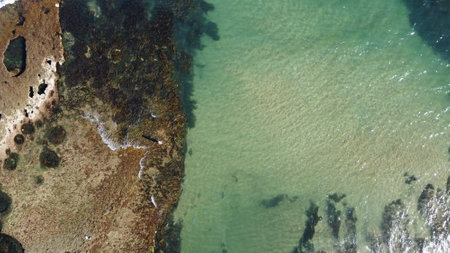 Lone fisherman standing on the edge of a rocky outcrop, casting his line into the ocean, waves crashing in as the tides comes in, Torquay, Great Ocean Road, Victoria, Australia.の写真素材