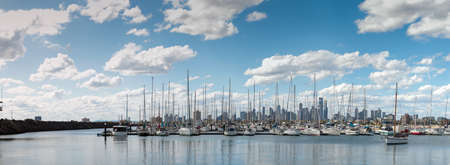 Panoramic of the city of Melbourne against a sunny blue sky seen from St Kilda pier looking through the masts of yachts in the bay, Melbourne, Victoria, Australiaの写真素材