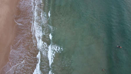 Surfers in the surf waiting for waves in the turquoise ocean off the Victorian Coastline, top down aerial drone viewの写真素材