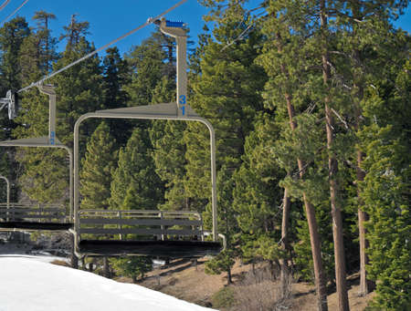 An empty chair on a ski lift during the winter with pine trees in the backgroundの写真素材