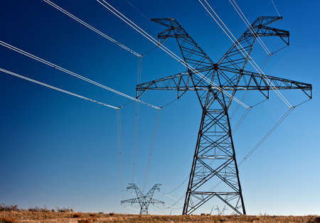 Several large high voltage power transmission towers silhouetted