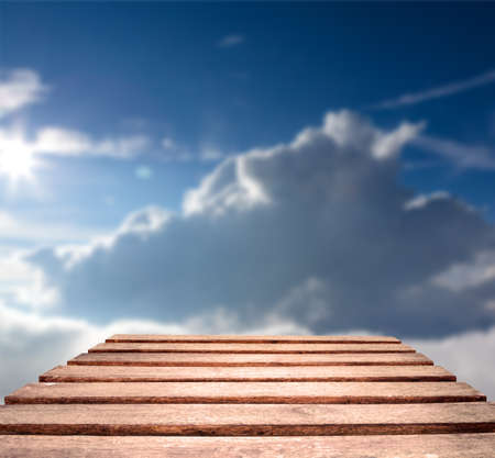 Old weather worn plank table top with blue sky in background   Focus is on planks in foregroundの写真素材