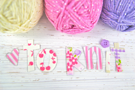 Crafts background with pastel colored yarn, heart and the word 'to knit'.の写真素材