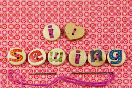 I love sewing spelled in hand painted letters on buttons on a vibrant textile background.の写真素材
