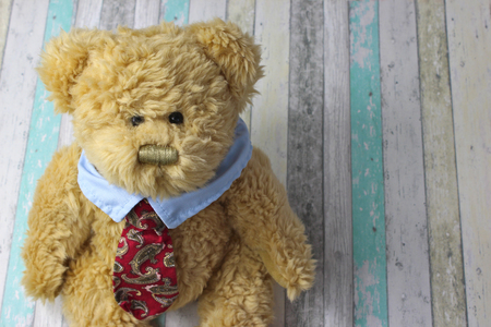 Office teddy bear dressed in shirt and tie against a rustic wooden background.の写真素材