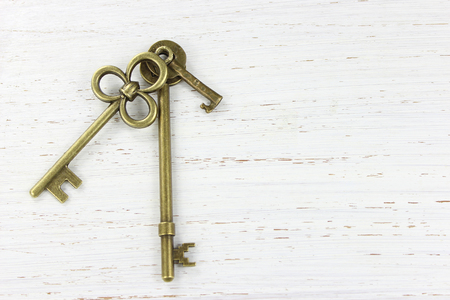 Three brass keys on a white distressed wood background. Copy space.の写真素材