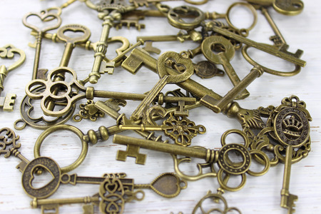 Pile of antique brass keys on a distressed white wood background.の写真素材