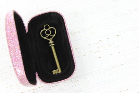 Antique brass key in glittery pink secret case on white distressed wood backgroundの写真素材