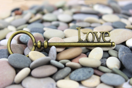 Love Key on a beach stone / pebble background. Great Valentines background. The key to Love.の写真素材