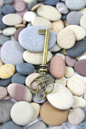 Antique brass key lying on pebbles beach stones on the beach.の写真素材