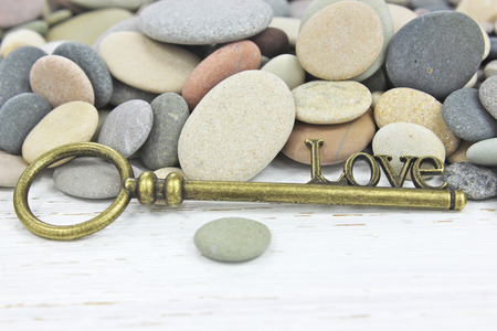 Antique Key to Love on a beach stone background with white distressed wood.の写真素材