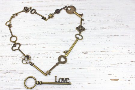 Heart shape of keys with key to Love on a white distressed wood background.の写真素材