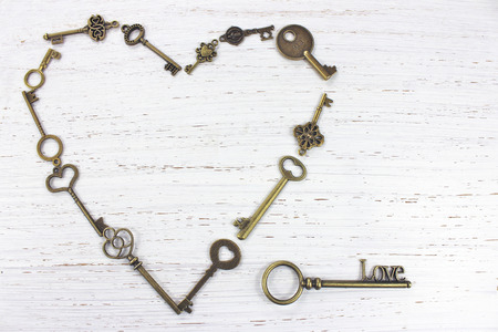 Heart shape made with old antique keys. Valentines day concept on a white distressed wood background.の写真素材