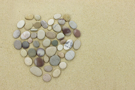 heart made of beach stones on a sandy beachの写真素材
