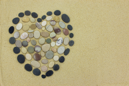 Heart shape made from beach stones or pebbles on golden sand.の写真素材