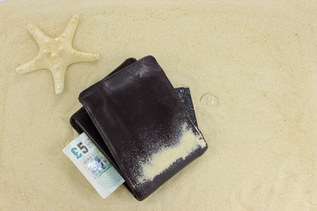 Wallet on the sand with five pound noteの写真素材