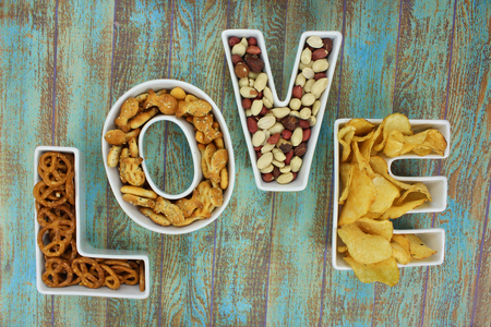 Snacks in Love shaped letter bowls on rustic turquoise wooden backgroundの写真素材