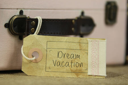 Paper tag with the handwritten words 'Dream vacation' on vintage suitcase.の写真素材