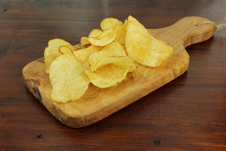 Rustic Potato chips or crisps on a dark wooden backgroundの写真素材
